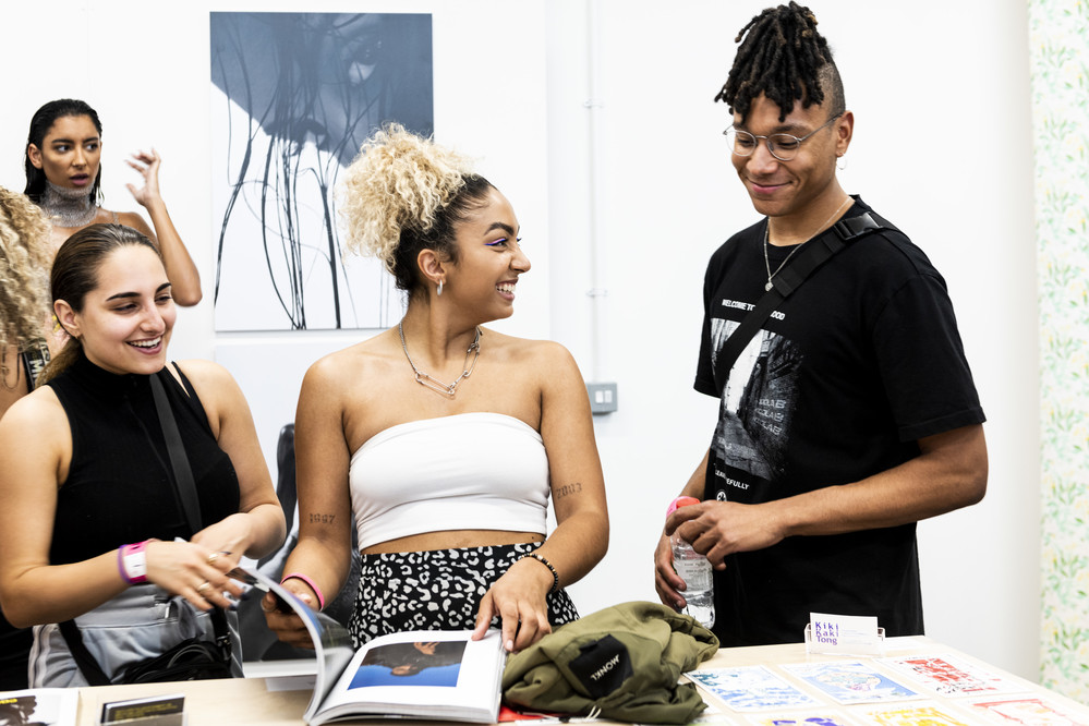 A group of students smiling and looking through course materials on a table.